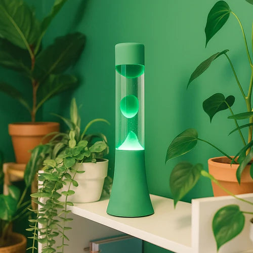 Een foto van de Fisura Groene Lavalamp tussen een aantal groene planten op een rekje.