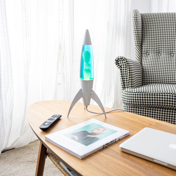 Een afbeelding van de Fisura Raket Lavalamp met Blauwe Lava - Chrome op een sallontafel in de leefruimte.
