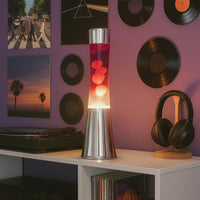 Fisura Grote Design Lavalamp met Witte & Rode Lava - Chrome op een kast naast platen, een hoofdtelefoon en een platenspeler