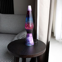 Een foto van de Fisura Kogelvormige Lavalamp met Paarse Lava & Glitter - Galaxy op een salontafeltje. 