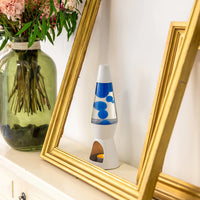 Een foto van de Fisura Theelicht Lavalamp met Blauwe Lava - Wit op een wand met een gouden kader errond. 