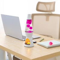 Een foto van de Fisura Theelicht Lavalamp met Roze Lava - Wit op een tafel naast een laptop. 